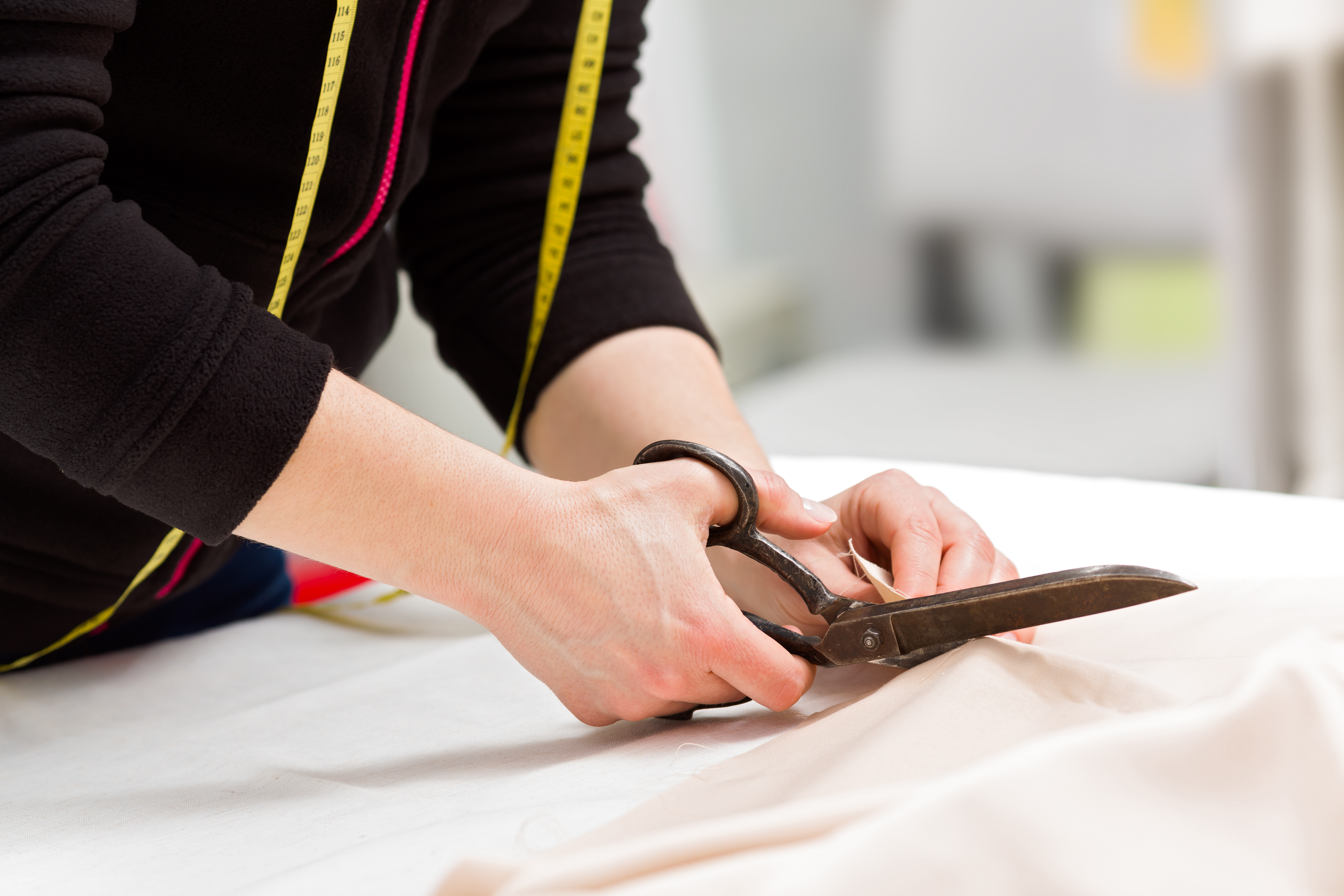 Dressmaker cutting fabric with scissors